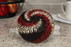 Round woven basket with black, red, and beige pattern on a kitchen counter.