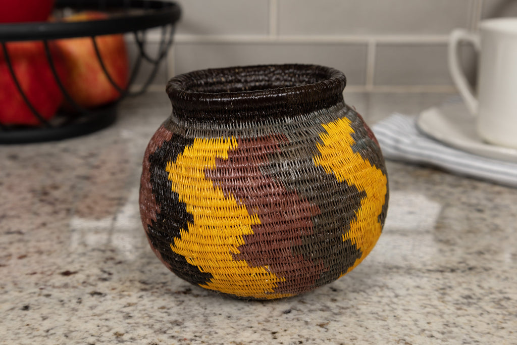 Woven basket with a yellow, black and brown geometric pattern on a kitchen counter