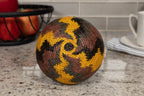 Woven basket with a yellow, black and brown geometric pattern on a kitchen counter