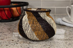 Decorative woven basket with black, brown, and white pattern on a kitchen counter.