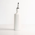 White ceramic olive oil bottle with a black lid on a white background