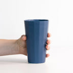 Hand holding a blue ceramic cup against a white background