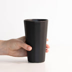 Hand holding a black tumbler against a white background