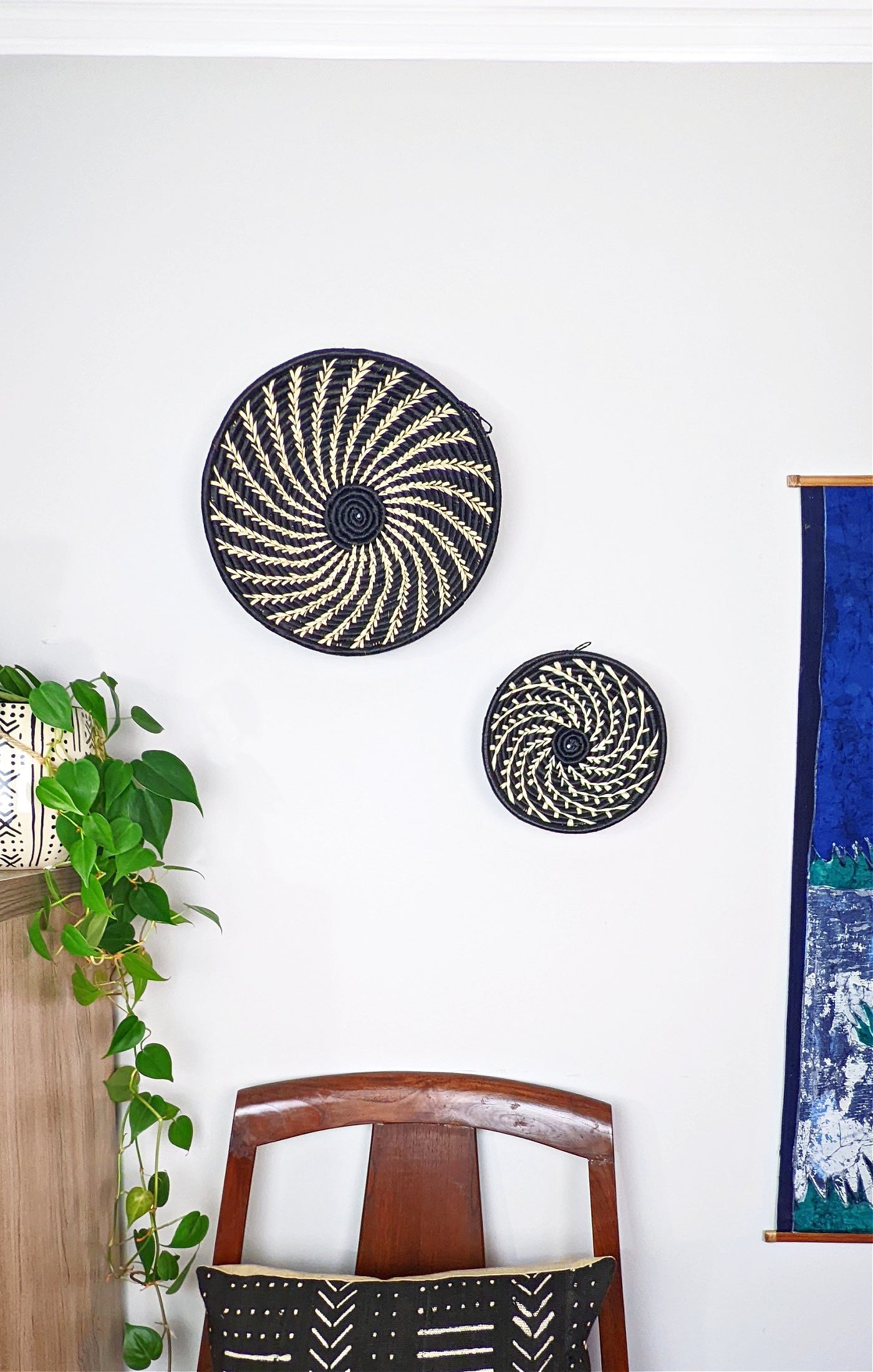 Decorative wall art with circular patterns on a white wall, featuring a plant and a chair.