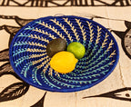 Decorative blue woven plate with a lemon, lime, and avocado on a patterned fabric background