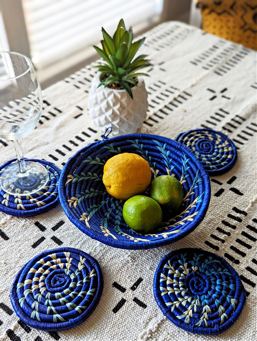 Blue woven bowl with fruits on a tablecloth with coasters