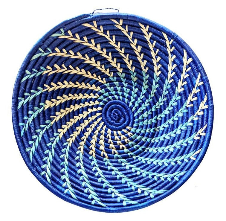 Round woven basket with blue and green spiral pattern on a white background