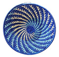 Round woven basket with blue and green spiral pattern on a white background