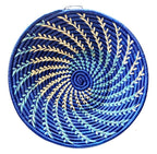 Round woven basket with blue and green spiral pattern on a white background