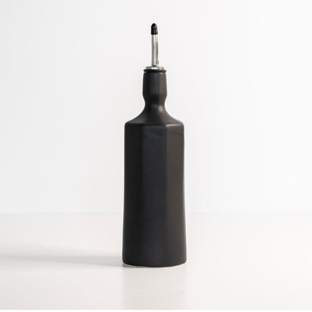 Black oil dispenser bottle with a silver-colored metallic nozzle on a white background