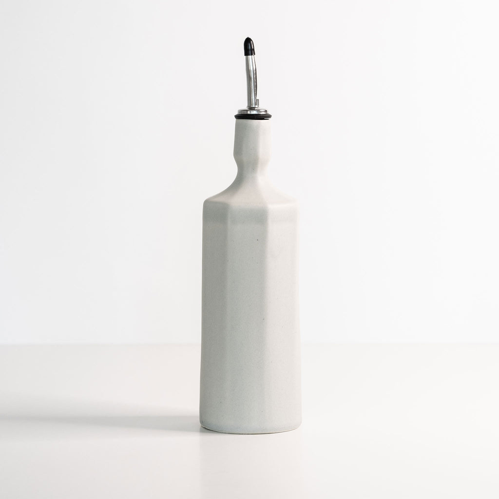 White ceramic oil dispenser bottle with a silver spout on a white background