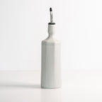 White ceramic oil dispenser bottle with a silver spout on a white background