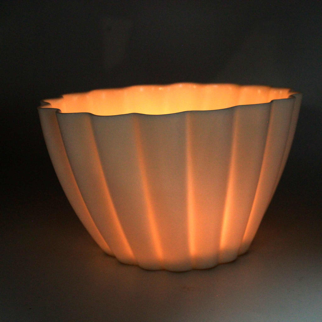 Ceramic bowl with ribbed texture glowing warmly on a dark background