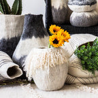 Decorative vases with textured finishes and plants on a light rug