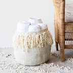 Textured vase with fringe on a rug next to a wicker chair