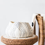 Textured white bowl with pattern on a cork base with a blurred background