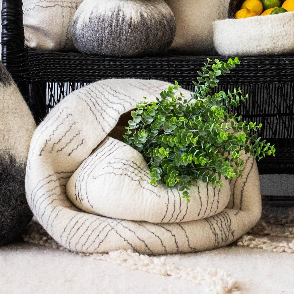 Decorative woven basket with textured fabric and a green plant on a neutral background