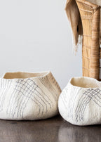 Two woven baskets with textured patterns on a neutral background