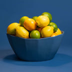 Blue bowl filled with lemons and limes on a blue background