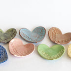 Set of heart-shaped ceramic dishes in various colors on a white background