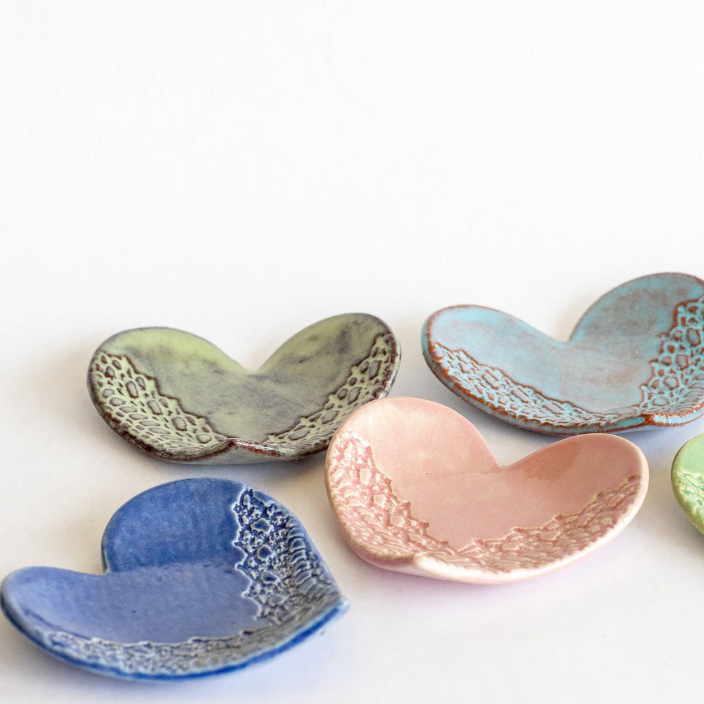 Set of ceramic heart-shaped dishes in various colors on a white background