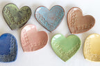 Set of ceramic heart-shaped dishes in various colors on a white background