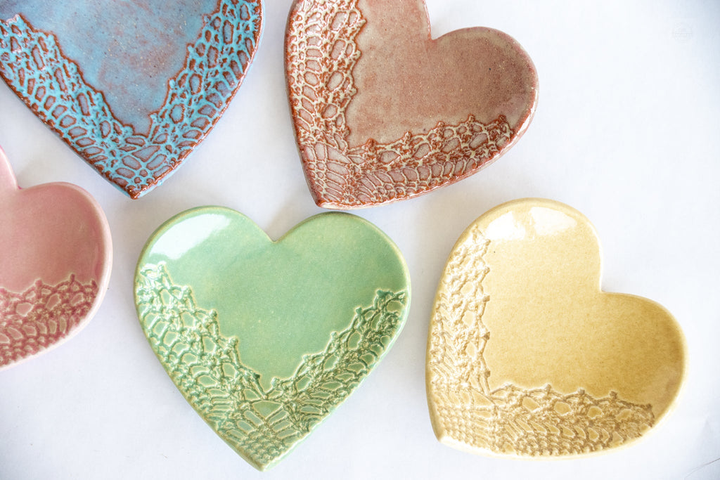 Heart-shaped ceramic dishes in various colors with textured edges on a white background