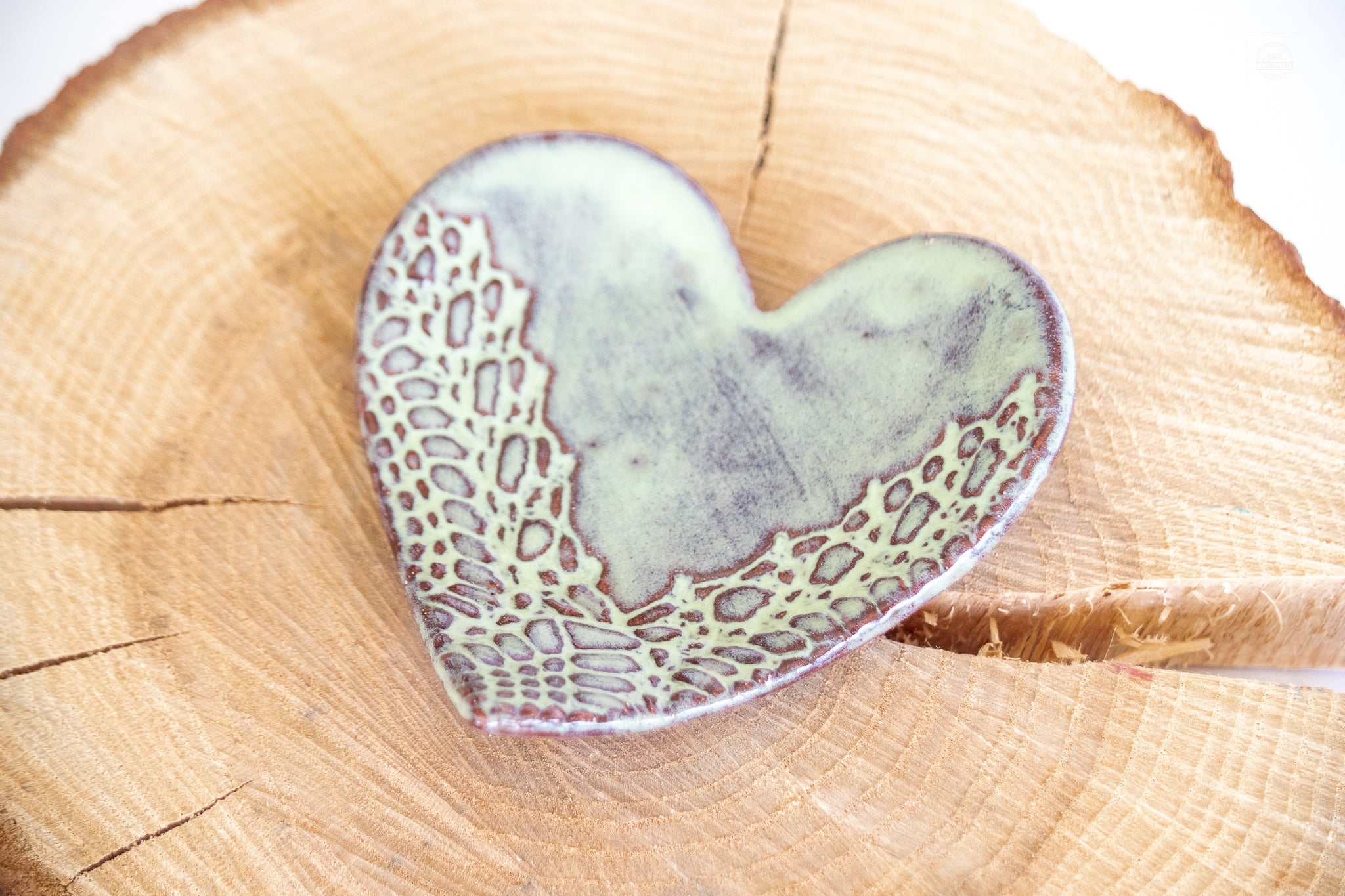 Heart-shaped ceramic piece with textured surface on a wooden background