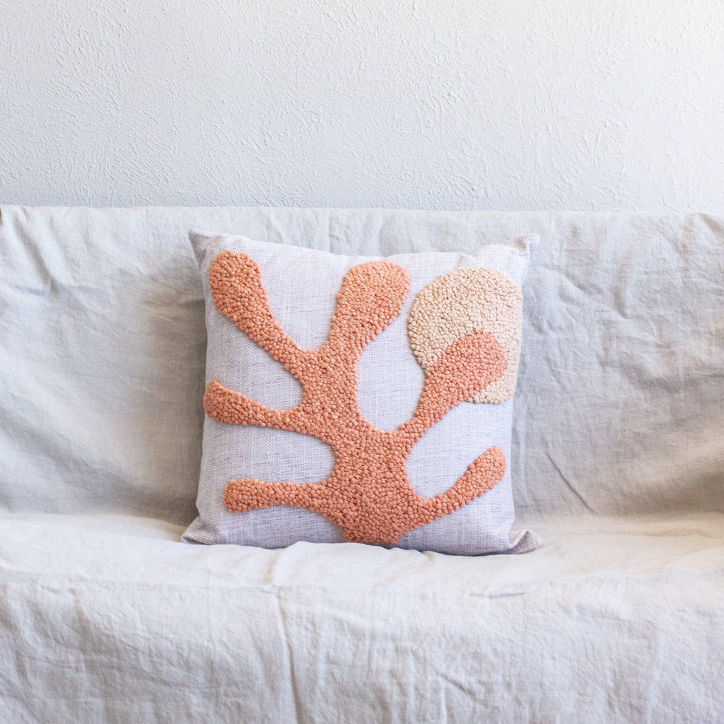 Decorative pillow with coral leaf pattern on a white couch