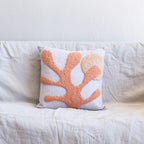 Decorative pillow with coral leaf pattern on a white couch