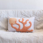 Decorative pillow with coral design on a white couch