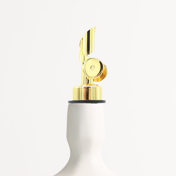 White oil dispenser with gold finish nozzle on a white background