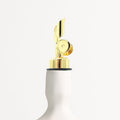 White oil dispenser with gold finish nozzle on a white background