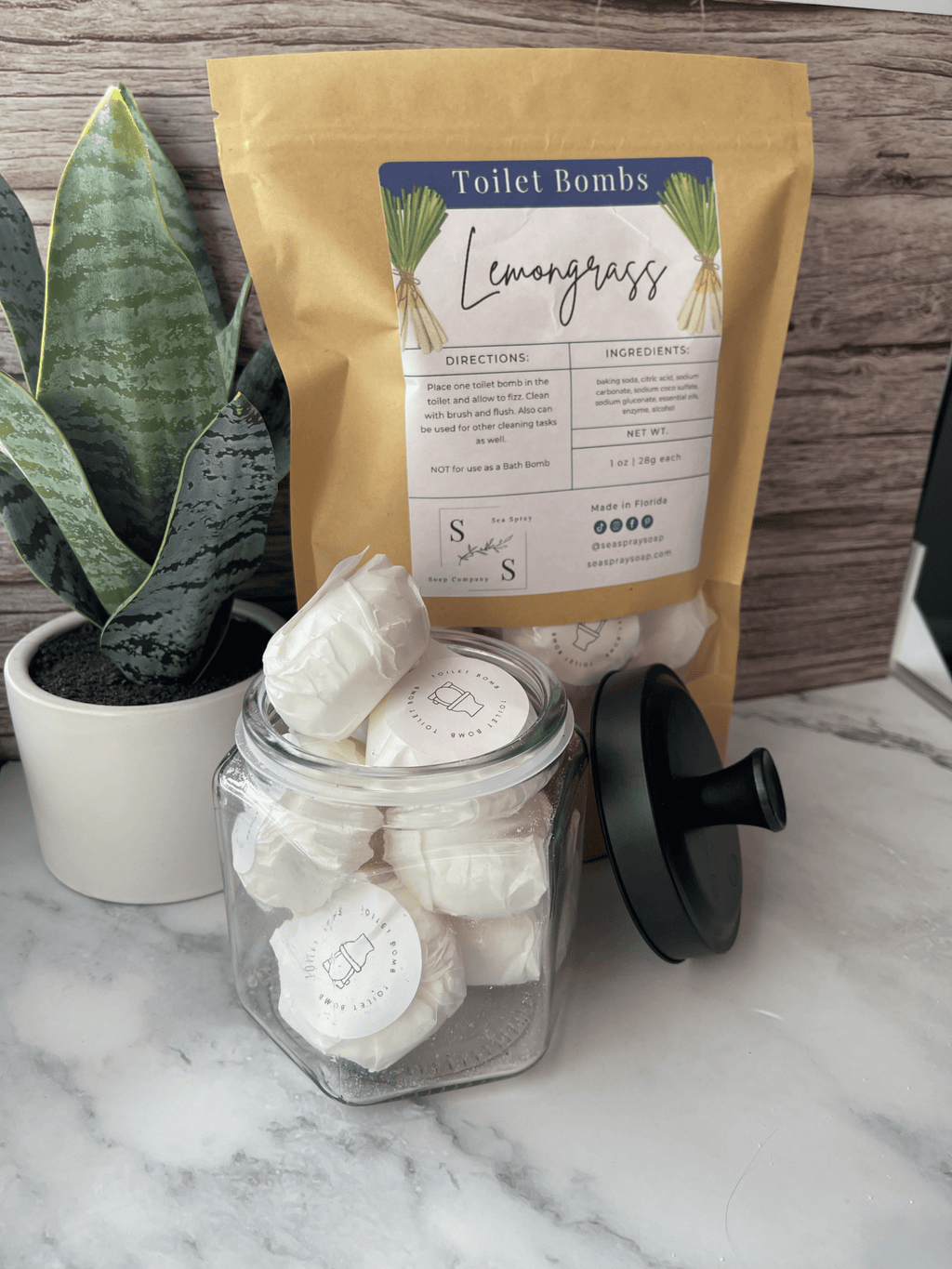 Jar of lemongrass toilet bombs with packaging on a marble surface