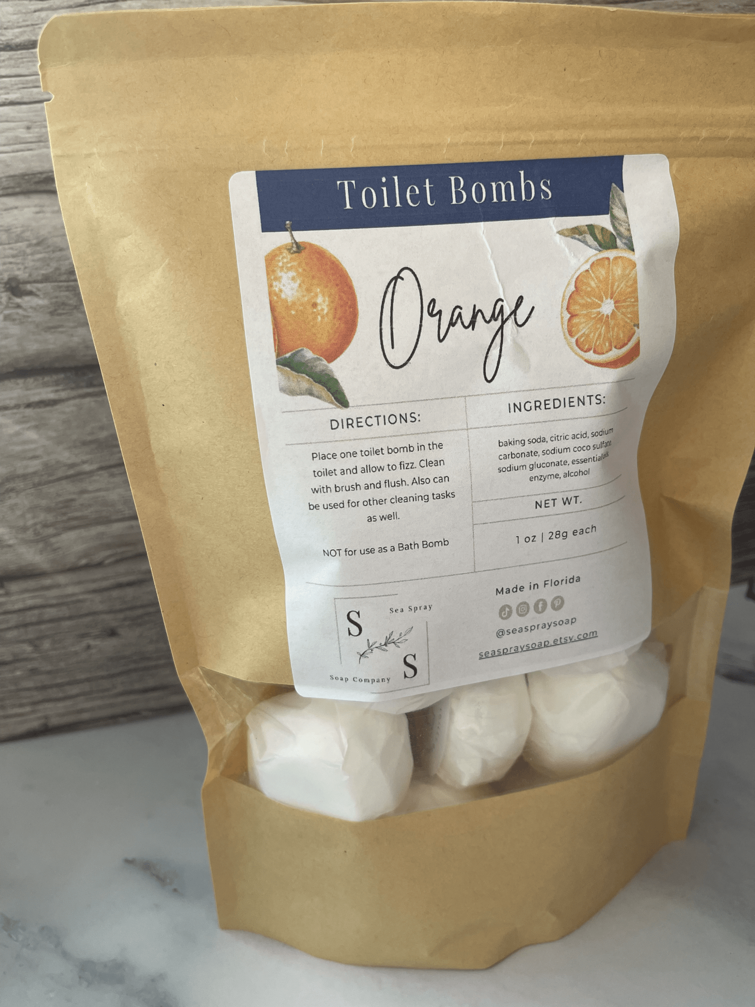Bag of orange-scented toilet bombs with a label on a marble surface.