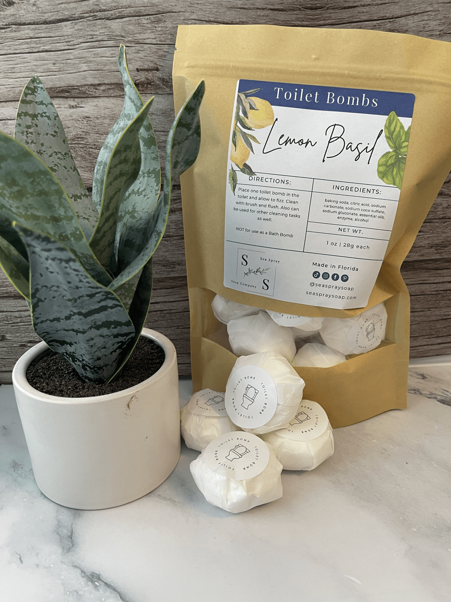 Bag of Lemon Basil Toilet Bombs with white bombs and a potted plant on a marble surface.