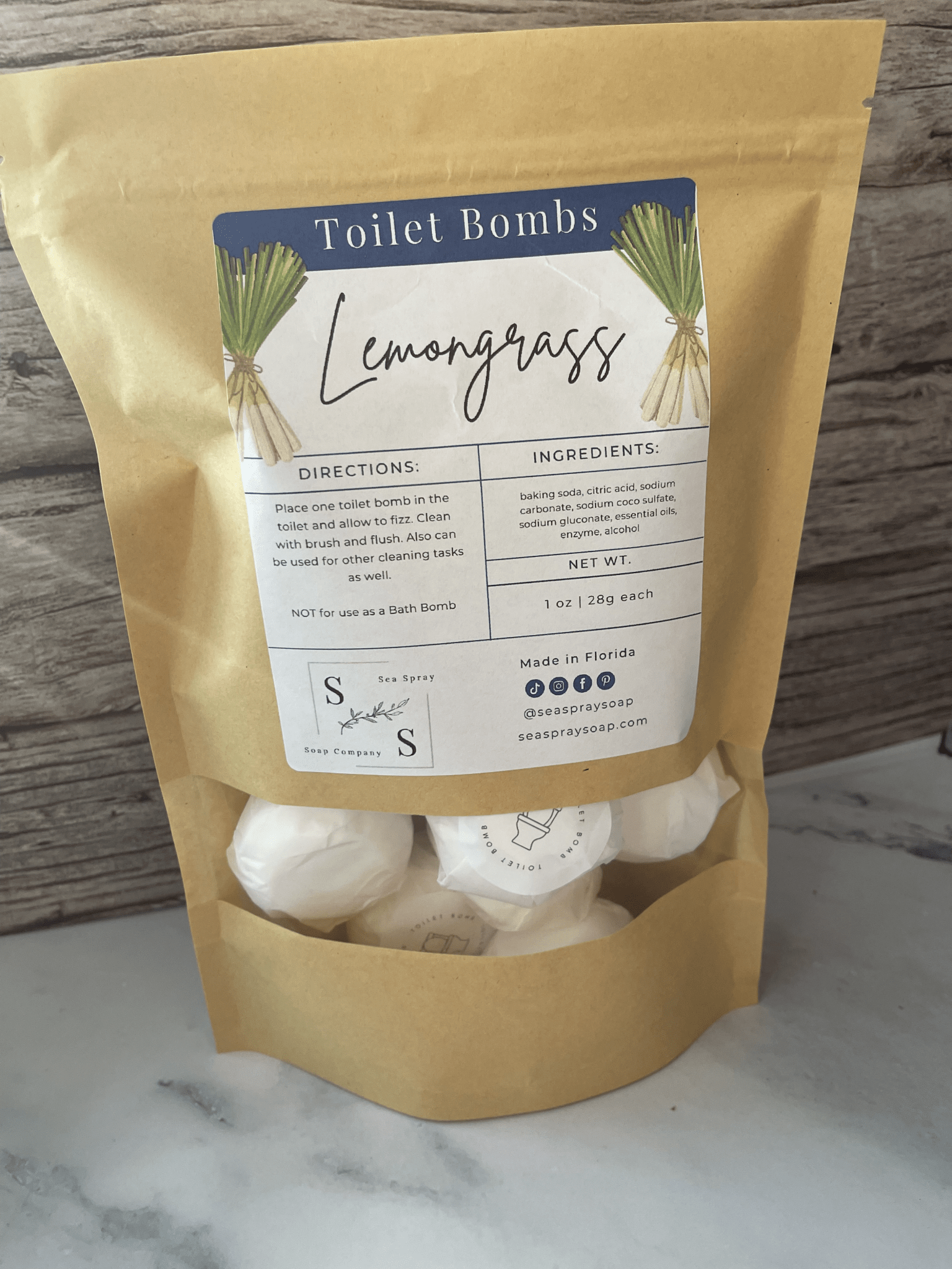 Packaged lemongrass toilet bombs with a label on a marble surface.