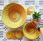 Yellow woven baskets with red and white patterns on a black and white patterned fabric background.