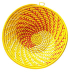Round woven basket with yellow, red, and white spiral pattern on a white background