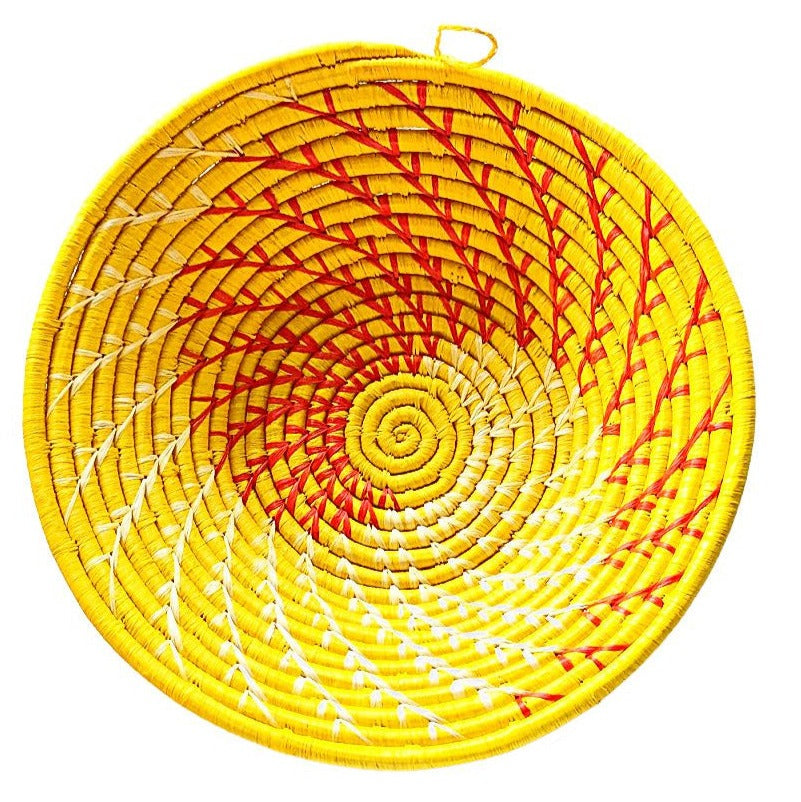 Round woven basket with yellow, red, and white spiral pattern on a white background